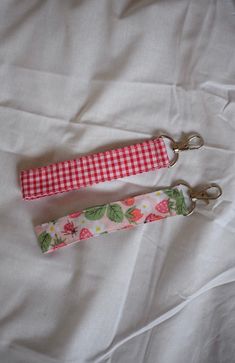 two key fobs on a bed with white sheets and red checkered fabric