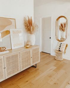 a living room with white walls and wood flooring is pictured in this image, there's a large mirror on the wall