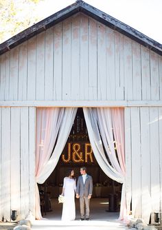 a bride and groom are standing in front of the barn door for their wedding ceremony