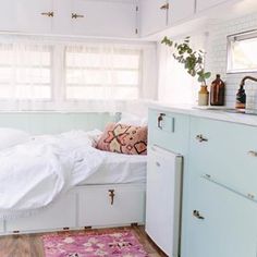 a bed sitting in the middle of a bedroom next to a sink and window with curtains