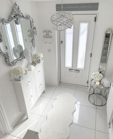 a white bathroom with a rug on the floor next to it and a large mirror