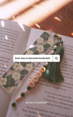 a bookmark with beads and tassels on it next to an open book