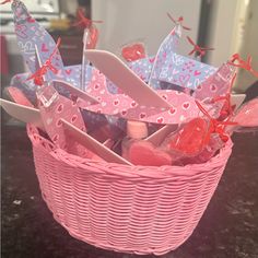 a pink basket filled with valentine's day items on top of a black table