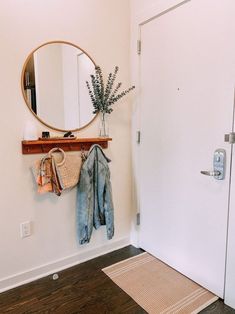 a mirror, coat rack and rug in a white room with wood flooring on the walls