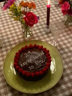 a birthday cake on a table with flowers in vases and candles around the plate