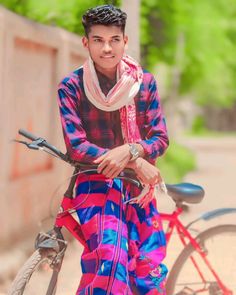 a man sitting on top of a bike next to a red and blue bicycle with a white scarf around his neck