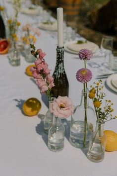 the table is set with several vases, plates and flowers on it for an elegant dinner