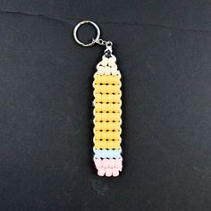 a keychain made out of legos on a black surface with the word lego written in white, yellow, and pink