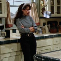 a woman standing in a kitchen with her arms crossed