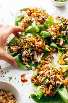 lettuce wraps filled with chicken, nuts and sauces on a white surface