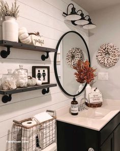 the bathroom is decorated with white pumpkins and wreaths on the shelf above the sink