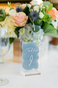 the table numbers are displayed in glass vases with flowers on them, along with wine glasses