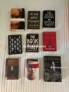 there are many books that are on the white bed sheet and one is in front of them