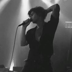 a woman singing into a microphone while standing in front of a stage with lights on