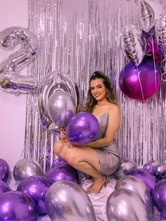 a woman sitting on the floor surrounded by balloons