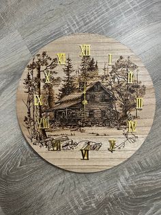 a wooden clock with a drawing of a cabin in the woods on it's face