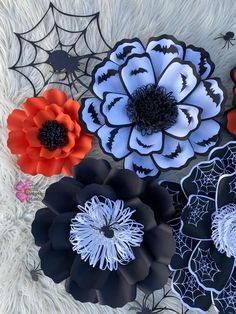 four paper flowers are laying on a white furnishing with spider webs in the background