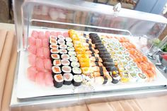 an assortment of sushi is displayed in a display case