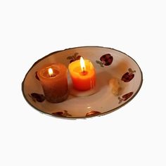 two lit candles sit on a plate next to each other