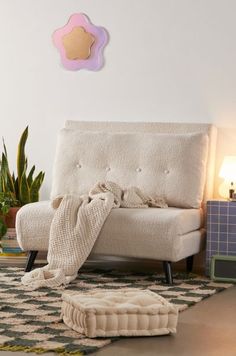 a white couch sitting on top of a rug next to a potted plant in a living room