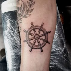 a black and white photo of a ship wheel tattoo