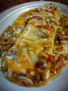 a white plate topped with meat and cheese covered enchilada casserole