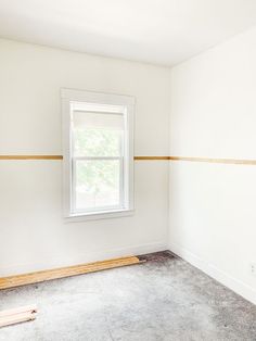 an empty room with white walls and a window in the corner that is being painted