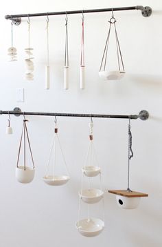 several hanging bowls and spoons are suspended from a metal bar on a white wall