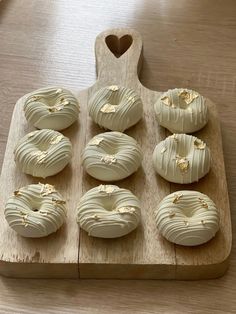 a wooden cutting board topped with donuts covered in white frosting