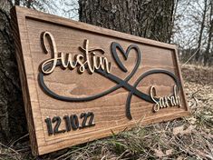 a wooden sign with the name and date engraved on it in front of a tree