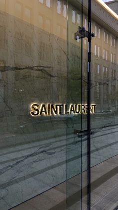 the reflection of a building in a glass window that says saint laurent on it's side