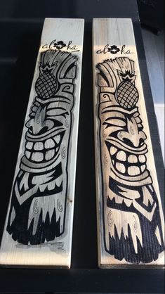 two wooden boards with designs on them sitting next to each other in front of a black table