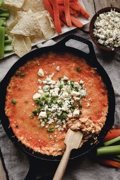 a skillet filled with cheese and vegetables next to tortilla chips