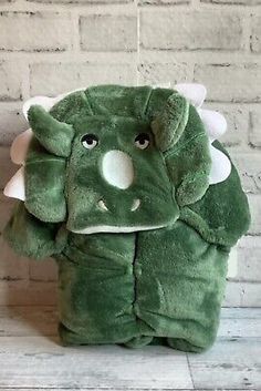 a green stuffed animal sitting on top of a white brick wall in front of a brick wall