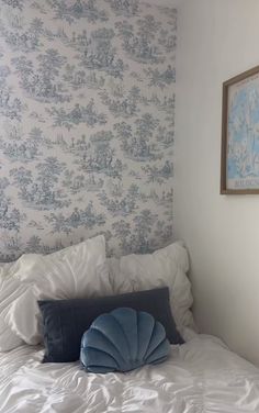 a white bed topped with pillows and a blue pillow sitting on it's side