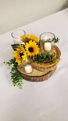 sunflowers and candles are arranged on a wood slice with greenery in the center