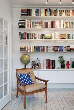 a living room filled with furniture and lots of books on the shelves next to a window