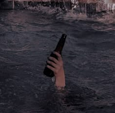 a person holding a beer bottle in the water