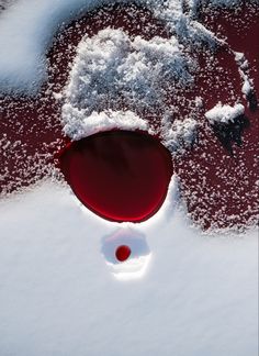 a red wine glass sitting in the snow with it's lid partially covered by snow