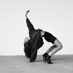 a woman in high heels doing a handstand on the ground with her legs up