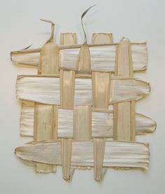 a piece of art made out of wood sticks and bamboo strips on a white wall