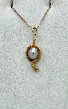 This is a rare antique Victorian Snake Pendant Necklace depicting a snake or serpent wrapped around an egg or globe. The snake is beautifully created in 14 Karat yellow gold. The egg or globe is a gorgeous Baroque Pearl of a stunning silver color. The snake pendant dates to circa 1850-1900. It is extremely rare to find these early snake jewels and we are so excited when we do. The combination of the stunning rendering of the golden snake with the silvery white hues of the natural baroque pearl create a wonderful antique jewel that is full of both drama and whimsy and the power and beauty of the natural world. And snake jewelry is all the rage today. In the Victorian era the snake was the symbol of eternal love. It has come to symbolize sexuality, rebirth and wisdom. The snake pendant is 1 Antique Egyptian Jewelry, 18th Century Jewelry Necklaces, Snake Pendant Necklace, Gilded Age Jewelry, Georgian Era Jewelry, Persian Jewelry Iran, Enchant Jewelry, Georgian Jewelry 18th Century, Snake Inspired Fashion