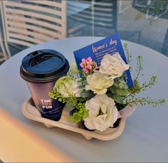 there is a coffee cup and some flowers on the table with a book in it