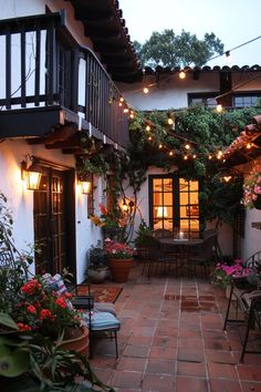 an outdoor patio with potted plants and lights strung from the ceiling over it's doors