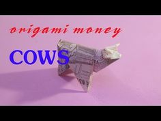 the origami money cow is made out of newspaper and sits on a pink surface