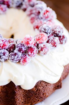 a cake with white frosting and cranberries on top sitting on a plate