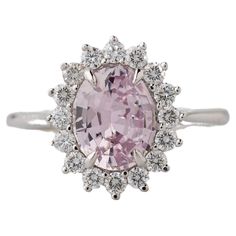 an oval shaped pink diamond surrounded by white diamonds in a halo setting on a silver band