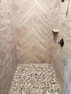 a walk in shower sitting next to a wall with pebbles on the floor and walls