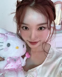 a woman holding a hello kitty stuffed animal