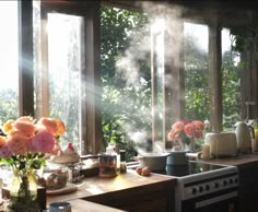 the sun shines through the windows in this kitchen with flowers and teapots on the counter